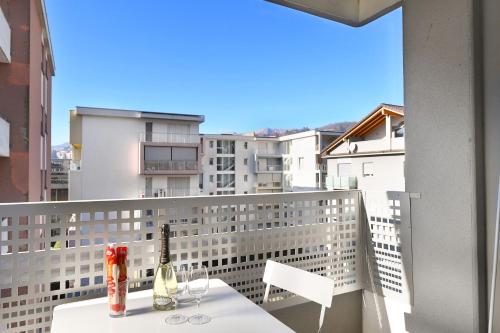 een balkon met een tafel en 2 flessen wijn bij Santi Apartment Few Min From Lake - Happy Rentals in Lugano