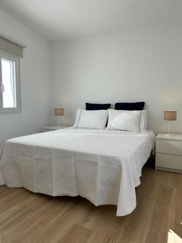 biała sypialnia z dużym białym łóżkiem z białą pościelą w obiekcie Vista del Mar Guest House w Albufeirze