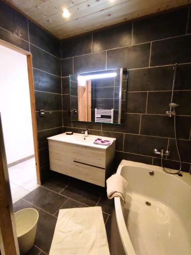 une salle de bain avec une baignoire, un lavabo et un miroir dans l'établissement Grand Studio Val Cenis, à Lanslebourg-Mont-Cenis