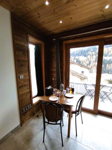une salle à manger avec une table et des chaises et une grande fenêtre dans l'établissement Grand Studio Val Cenis, à Lanslebourg-Mont-Cenis