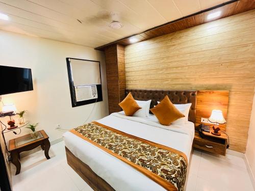 a bedroom with a large bed and a flat screen tv at Airport Hotel Nysha Palace in New Delhi