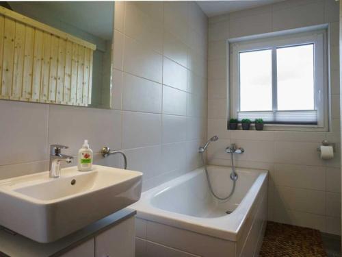 uma casa de banho branca com um lavatório e uma banheira em Ferienhaus "Felix" mit freiem Blick em Korswandt