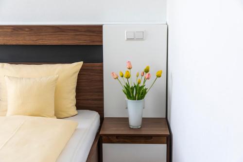 a bed with a vase of flowers on a table at Hotel JÄGERHAUS in Singen am Hohentwiel in Singen