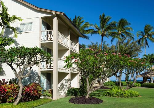 a building with palm trees and flowers at Aston Islander On The Beach in Kapaa