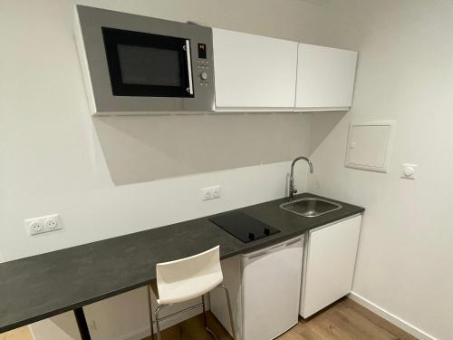 eine kleine Küche mit einer Spüle und einer Mikrowelle in der Unterkunft Studio meublé Longwy-Haut Centre in Longwy