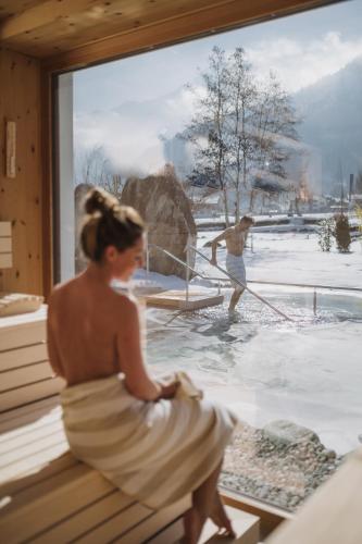 a woman sitting on a window with a man in the water at Rieser Achensee Resort in Pertisau