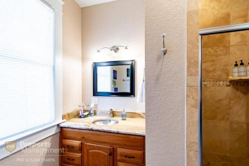 a bathroom with a sink and a shower with a mirror at Breakfast Club - U of Tampa Flat in N Hyde Park in Tampa