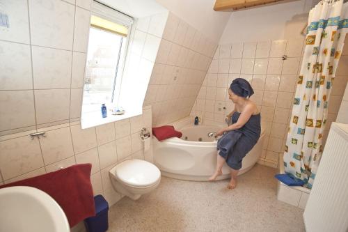 a woman sitting on a tub in a bathroom at Ferienwohnung Luxusdomizil Rathausblick in Otterndorf