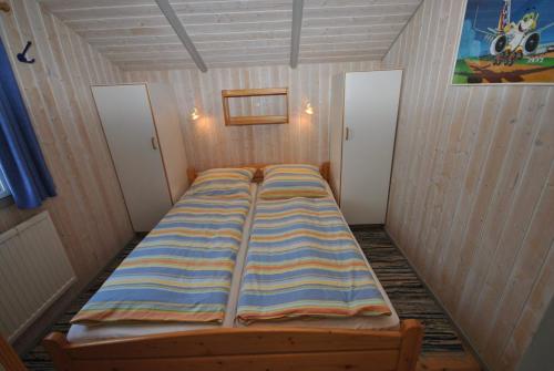 Bett in einem kleinen Zimmer mit zwei Türen in der Unterkunft Ferienhaus Korsör in Otterndorf