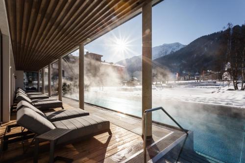 a resort with a swimming pool and snowy mountains at Rieser Achensee Resort in Pertisau