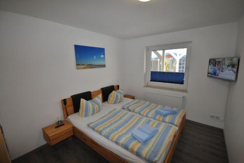 Un dormitorio con una cama con almohadas azules y una ventana en Ferienhaus Seestern I, en Otterndorf