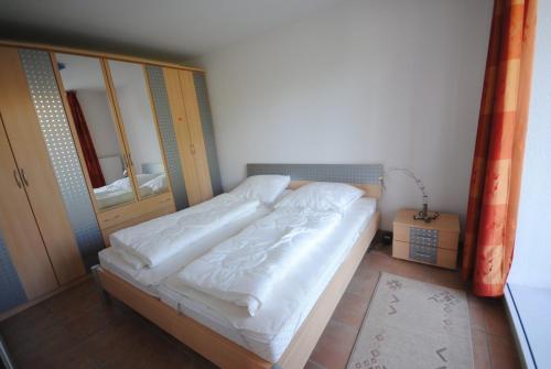 een kleine slaapkamer met een bed met witte lakens bij Ferienwohnung Korte in Otterndorf