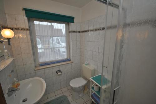 łazienka z toaletą, umywalką i oknem w obiekcie Medemstern I w mieście Otterndorf
