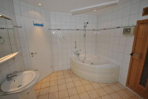 ein weißes Badezimmer mit einer Badewanne und einem Waschbecken in der Unterkunft Ferienhaus Strandperle in Otterndorf