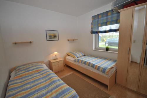 - une chambre avec 2 lits et une fenêtre dans l'établissement Ferienhaus Strandperle, à Otterndorf