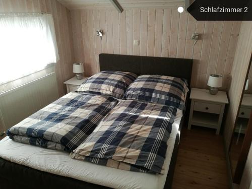 ein Schlafzimmer mit einem Bett mit einer karierten Decke in der Unterkunft Ferienhaus Südsee 26 in Otterndorf