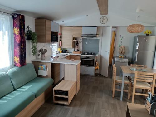 a kitchen and living room with a couch and a table at Mobile Homes Sous le Soleil in Valras-Plage