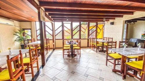 a dining room with tables and chairs and windows at Pousada dos Atobás in Arraial do Cabo