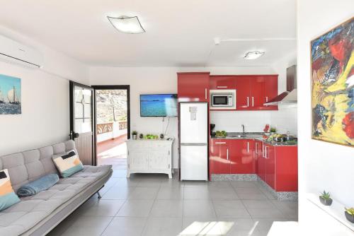 a kitchen with red cabinets and a couch in a room at Beach Apartment in Playa del Cura 323 in Mogán