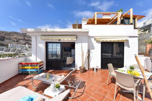 a house with a patio with chairs and a table at Beach Apartment in Playa del Cura 323 in Mogán