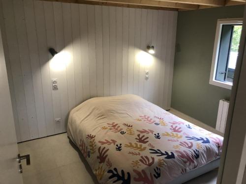 Un dormitorio con una cama con una manta. en Chalet 4 pers Locmariaquer, OLLC, en Locmariaquer