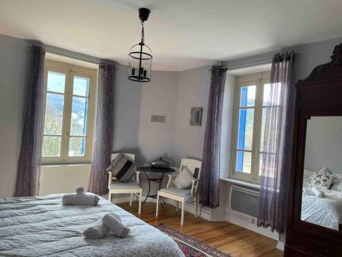 Schlafzimmer mit einem Bett, einem Tisch und Fenstern in der Unterkunft Charming holiday home in a beautiful setting in Axat