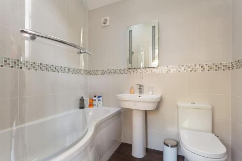 a white bathroom with a sink and a toilet and a tub at The Stables - 2 bed with large garden and hot tub. in Sway