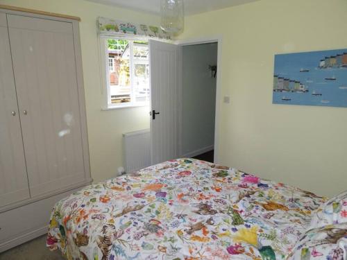 a bedroom with a bed with a floral comforter at The Stables - 2 bed with large garden and hot tub. in Sway