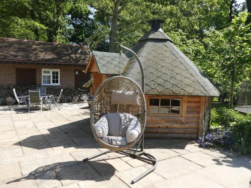a wicker chair in front of a small house at The Stables - 2 bed with large garden and hot tub. in Sway