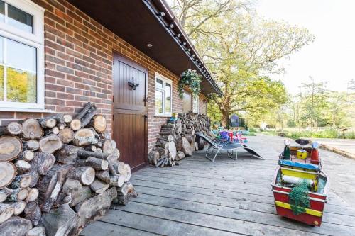 a deck with a pile of logs next to a house at The Stables - 2 bed with large garden and hot tub. in Sway