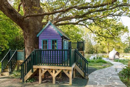 a purple house sitting on a bench next to a tree at The Stables - 2 bed with large garden and hot tub. in Sway