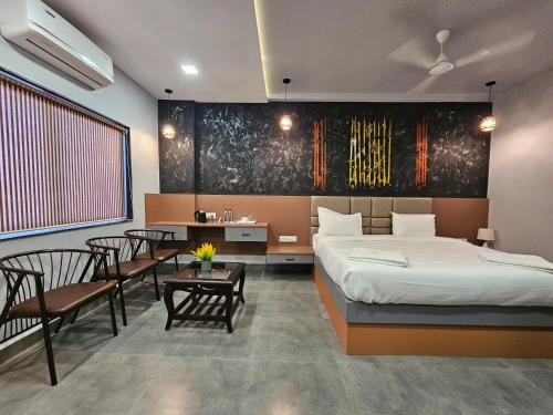 1 dormitorio con 1 cama, mesa y sillas en Hotel KT's Happy Stay Kolhapur 2 km from kolhapur airport en Kolhapur