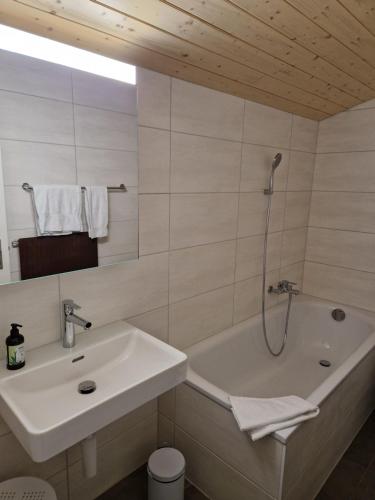 a bathroom with a sink and a bath tub at Auberge du Peu-Péquignot in Le Noirmont