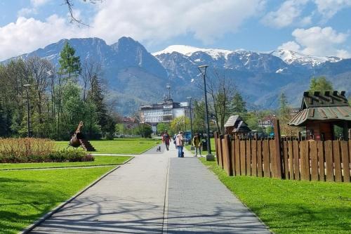 people walking down a sidewalk with mountains in the background at Sunny Apartment Centrum Zakopane in Zakopane