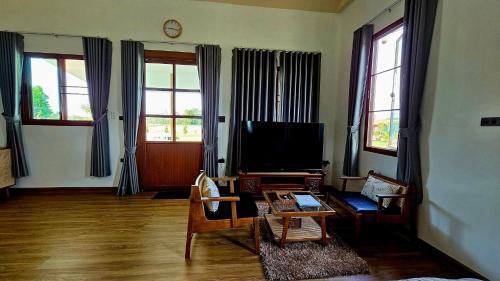 un soggiorno con TV, divano e sedie di บ้านสวนลุงแจน ฟิชชิ่งพาร์ค แอนด์ รีสอร์ท 