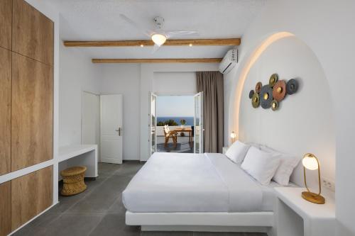 a white bedroom with a bed and a table at Sonus Mare Beach Apartments, Vourvoulos Beach in Vourvoúlos