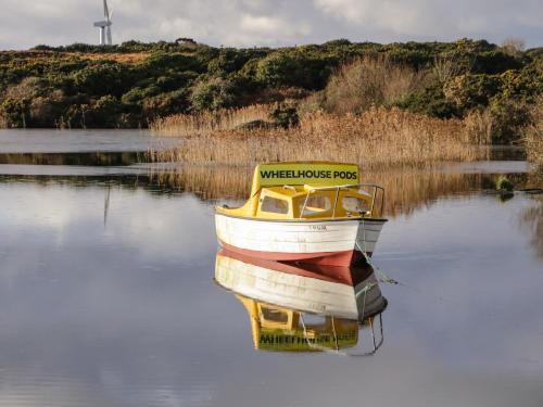 a boat sitting in the water with a windmill in the background at The Wheelhouse Pod No 6 in Letterkenny