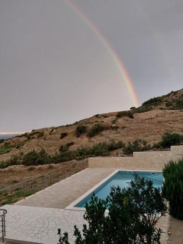 un arcobaleno sopra una piscina con piscina di Apartment Ante K A1 a Metajna