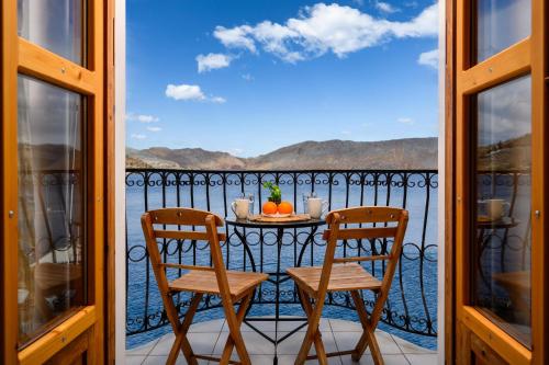 a table and chairs on a balcony with a view of the water at OverThe Sea Apartments in Symi
