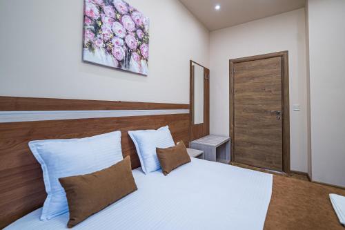 a bedroom with a white bed and a wooden headboard at Слънчевите Къщи in Banya