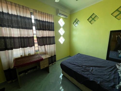 a bedroom with a bed and a desk and windows at HAB Guesthouse in Alor Setar