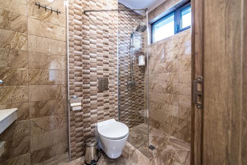 a bathroom with a toilet and a glass shower at Слънчевите Къщи in Banya