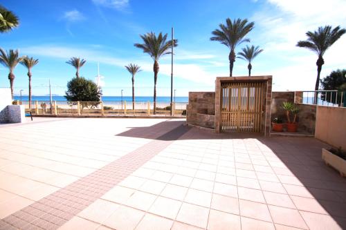 un patio con palmeras y la playa en Apartamento CasaTuris en 1ª Línea Muchavista Edificio Voramar C106, en El Campello