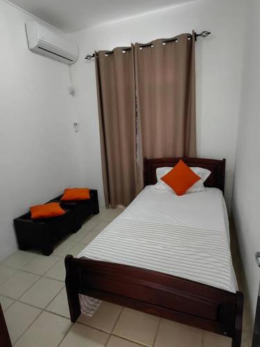 Un dormitorio con una cama con una almohada naranja. en La Salida House by SOV, en Pereybere