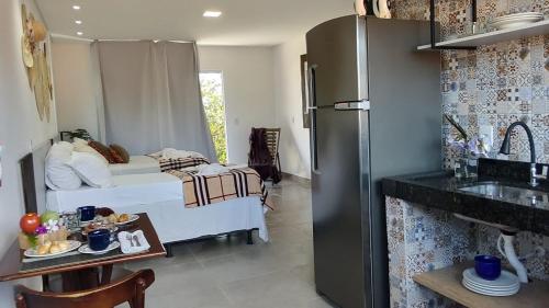 a small kitchen with a bed and a refrigerator at Pousada Coração do Rosa in Praia do Rosa