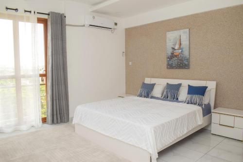 um quarto com uma grande cama branca com almofadas azuis em THE NEST, Beachfront Serviced Apartment in Nyali - with Panoramic Ocean view em Mombaça