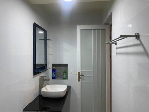 W białej łazience znajduje się umywalka i lustro. w obiekcie Dive Residence - Fuvahmulah, Maldives w mieście Fuvahmulah