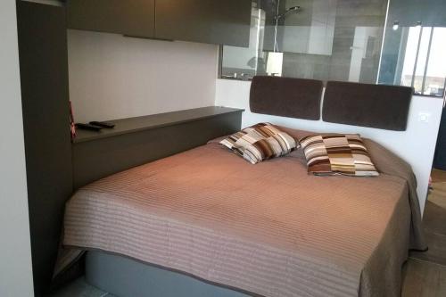 un lit avec deux oreillers dessus dans une chambre dans l'établissement Studio 216, Héliopolis AB au village naturiste, au Cap d'Agde