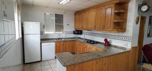 cocina con armarios de madera y nevera blanca en Casa Rural Villa Micleta en Callosa de Ensarriá