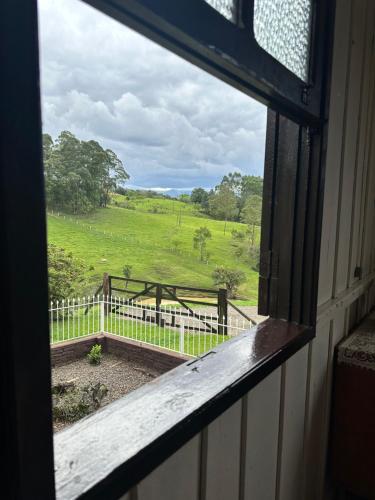a window with a view of a field with a fence at Morada Ignese in Siderópolis